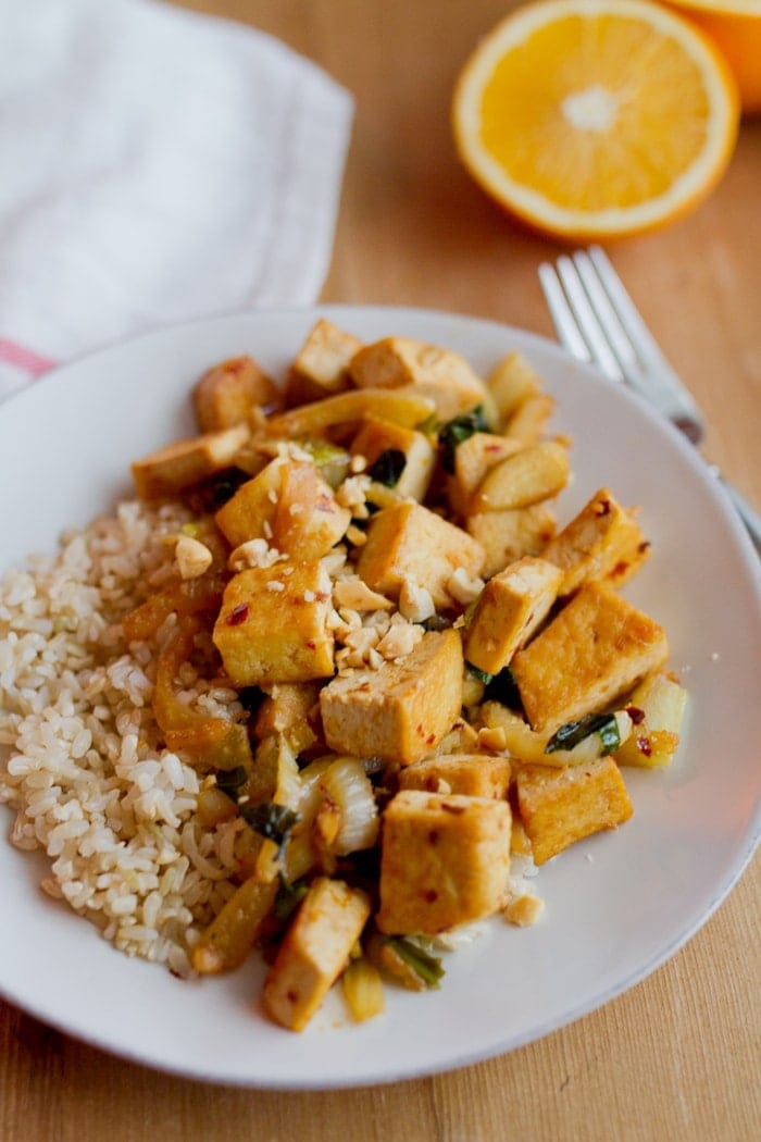Clean Eating Orange Tofu with Fennel and Basil Orange tofu stir-fried with fennel and served over brown rice on the white plate.