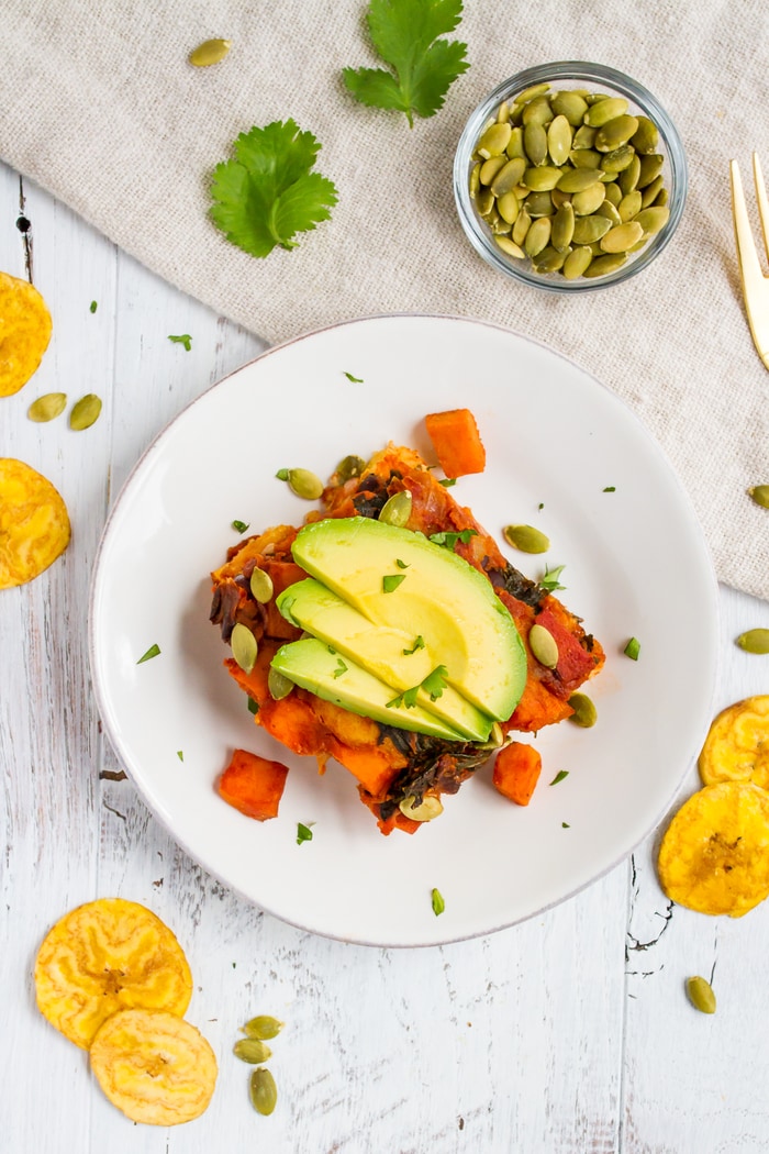 Overhead photo of Mayan harvest bake on a white plate with plantain chips scattered around.