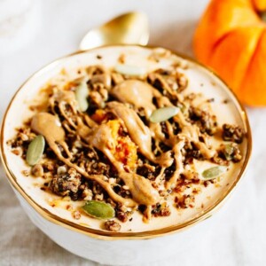 Pumpkin pie yogurt bowl topped with pumpkin seeds, granola and a drizzle of almond butter.