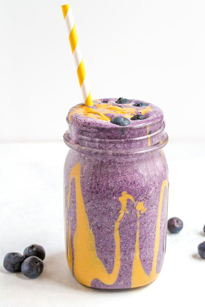 PEANUT BUTTER AND JELLY PROTEIN SMOOTHIE A blueberry smoothie with a peanut butter drizzle on the inside of the jar, topped with fresh blueberries.