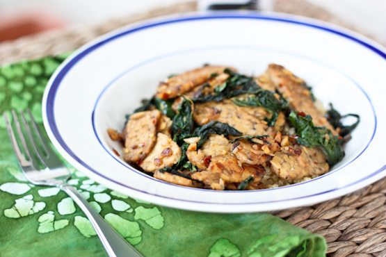 A flavorful one skillet meal with tempeh, sautéed kale and coconut aminos. Tempeh, sautéed kale and coconut aminos served in a white bowl.