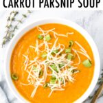 Bowl of carrot parsnip soup topped with green onion and cheese.