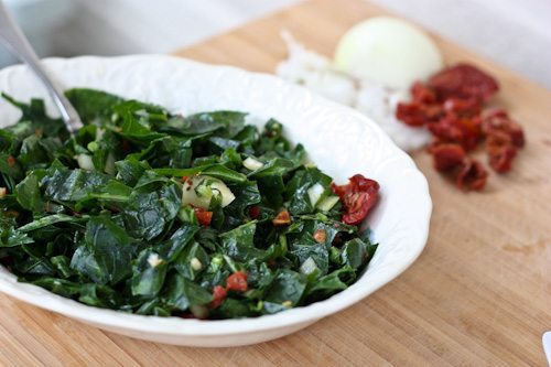 Raw collard greens salad served in a white bowl.