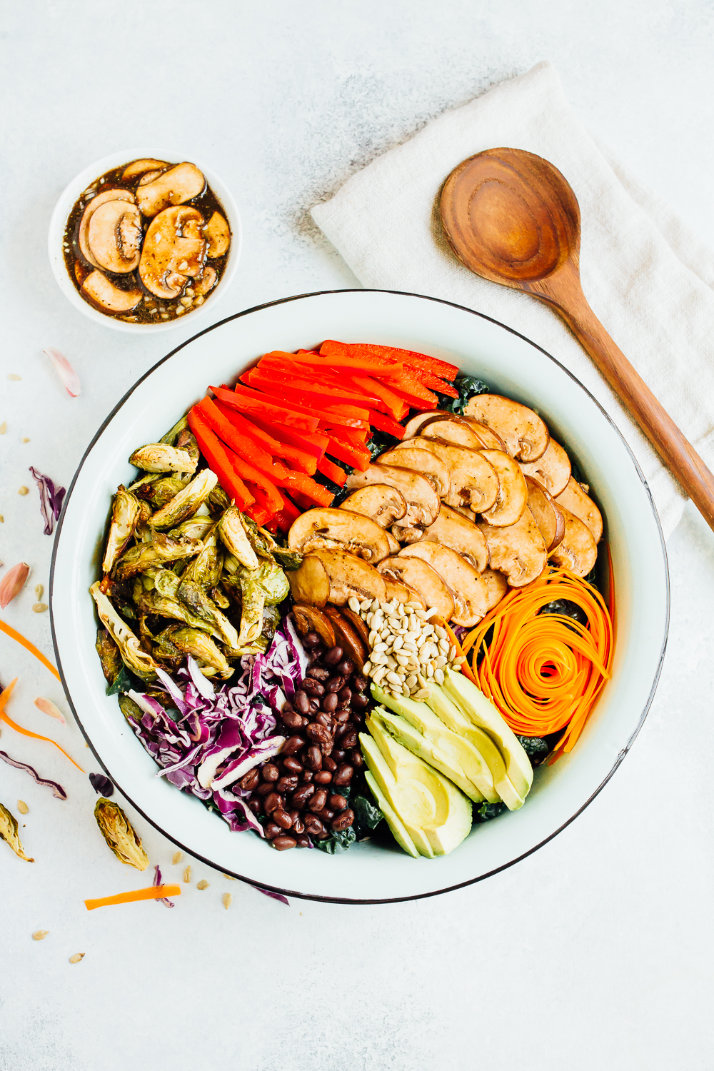 Pin this image to save this delicious kale detox salad recipe for later! Overhead photo of a large bowl with ingredients sliced and spread about the bowl.