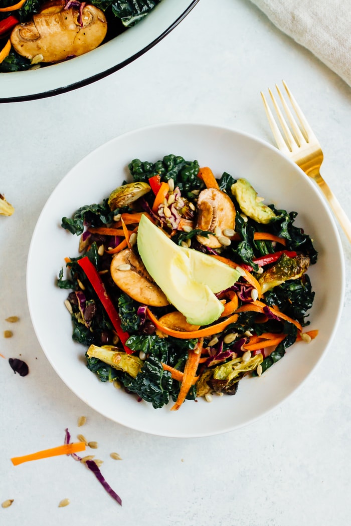 Save this delicious detox kale salad recipe for later! Overhead photo of single serving of detox kale salad with sliced avocado on top.