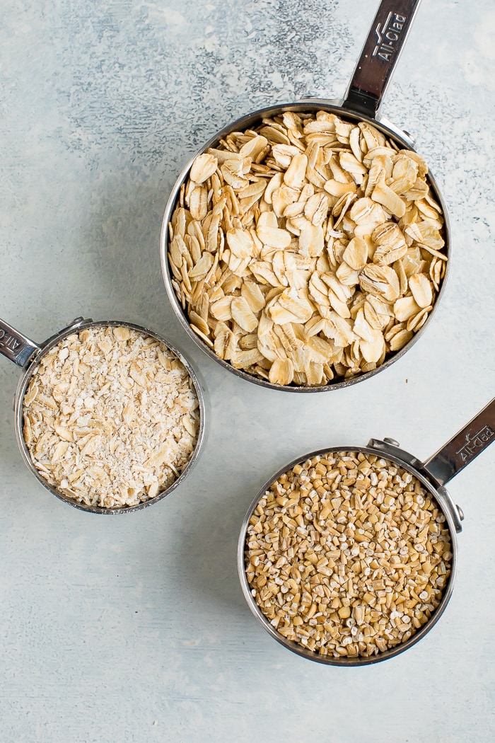 3 measuring cups with rolled oats, steel cut oats and quick oats.
