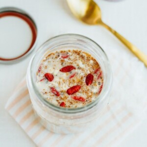 A mason jar with milk, oats, and goji berries.