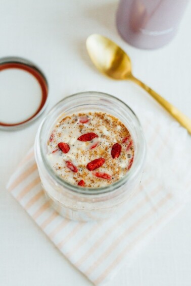 A mason jar with milk, oats, and goji berries.