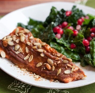 Pumpkin spice salmon served on a white plate alongside a green salad.