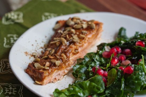 Pumpkin spice salmon served on a white plate alongside a green salad.