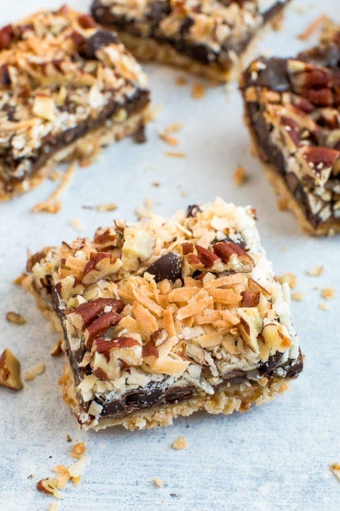 A cookie bar with almond flour cookie crust topped with coconut caramel, coconut, pecans, and chocolate chips.