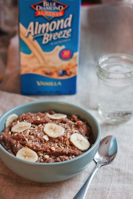 Banana Almond Teff Porridge in a light blue bowl with an almond milk container in background.