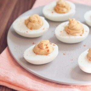 Hummus deviled eggs served on a white plate with a pink napkin underneath.