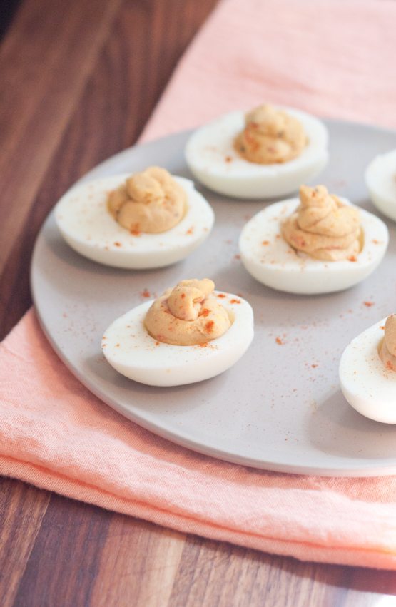 2 Ingredient Hummus Deviled Eggs Hummus deviled eggs served on a white plate with a pink napkin underneath.