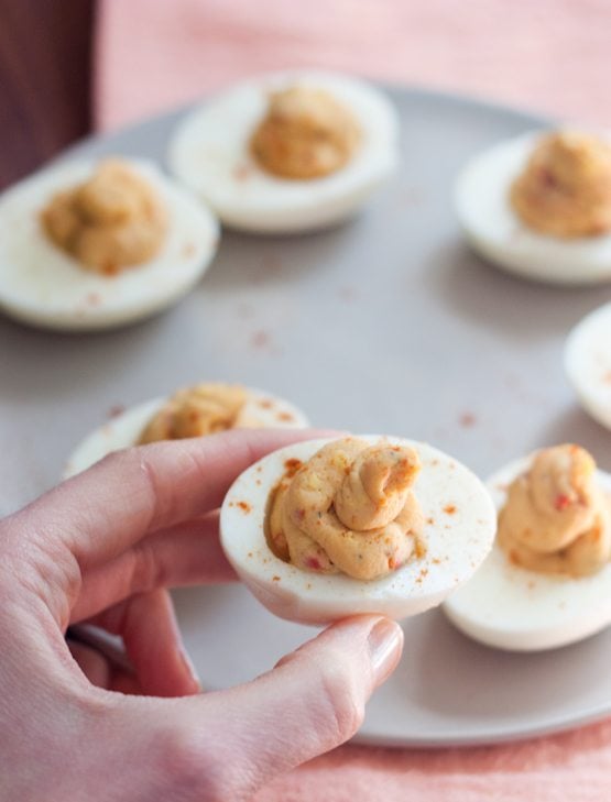 2 Ingredient Hummus Deviled Eggs A woman\'s hand holding a hummus deviled egg.