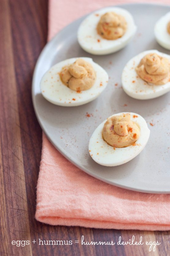 2 Ingredient Hummus Deviled Eggs Hummus deviled eggs served on a white plate topped with a dash of paprika.