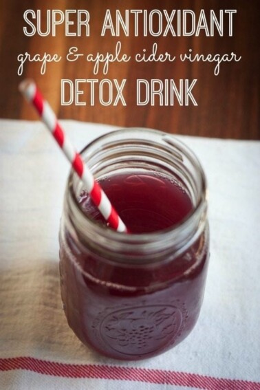 ACV and grape antioxidant drink served in a mason jar with a red and white straw.
