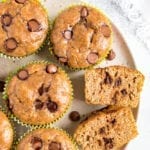 Plate of chocolate chip flourless zucchini muffins. One muffin is sliced in half and you can see the chocolate chips.