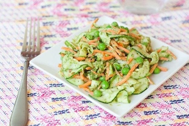 A plate of carrot and zucchini noodle pappardelle with pesto with a fork.