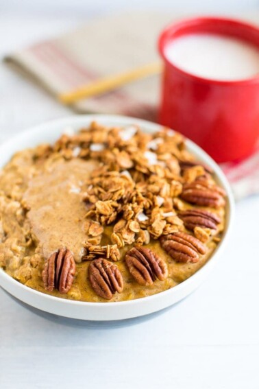 A serving of protein pumpkin oatmeal in a bowl with pecans and granola.