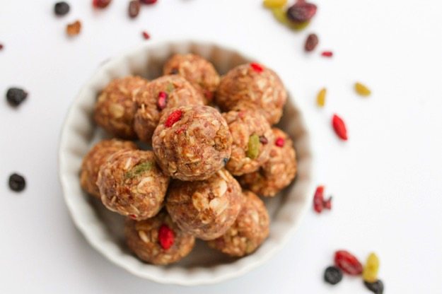 PIN THIS--> Superfood Energy Balls White bowl of Superfood Energy Balls with scattered superfood berries around the perimeter.