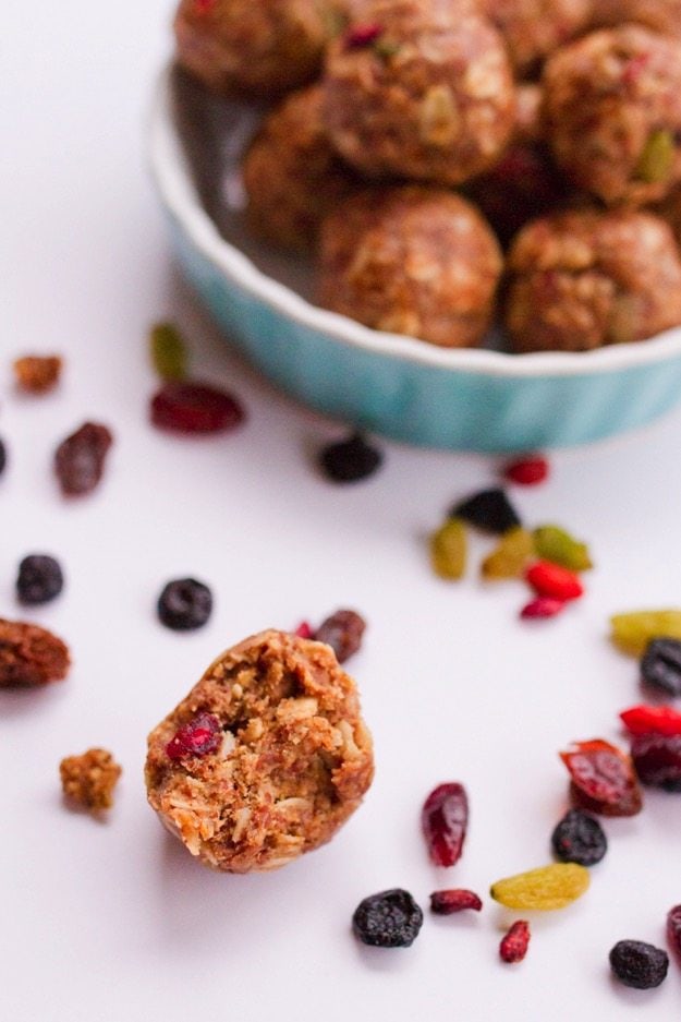 PIN THIS--> Superfood Energy Balls One superfood energy ball with a bite out of it in the foreground, superfood berries and a shallow bowl of superfood energy balls in the background.