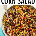 Serving bowl with black bean and corn salad. Spoon is in the bowl.