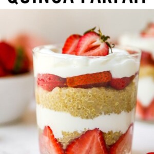 Strawberry, yogurt and quinoa parfaits, layered in a two glasses. A bowl of strawberries is behind the two parfaits.