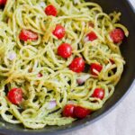 Rutabaga Pasta with a Creamy Pesto Sauce in a sauté pan with red onion and tomatoes.