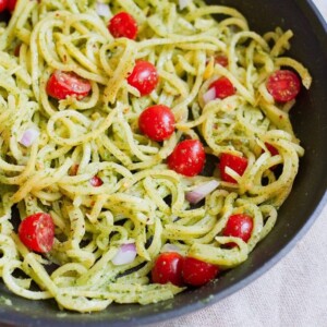 Rutabaga Pasta with a Creamy Pesto Sauce in a sauté pan with red onion and tomatoes.