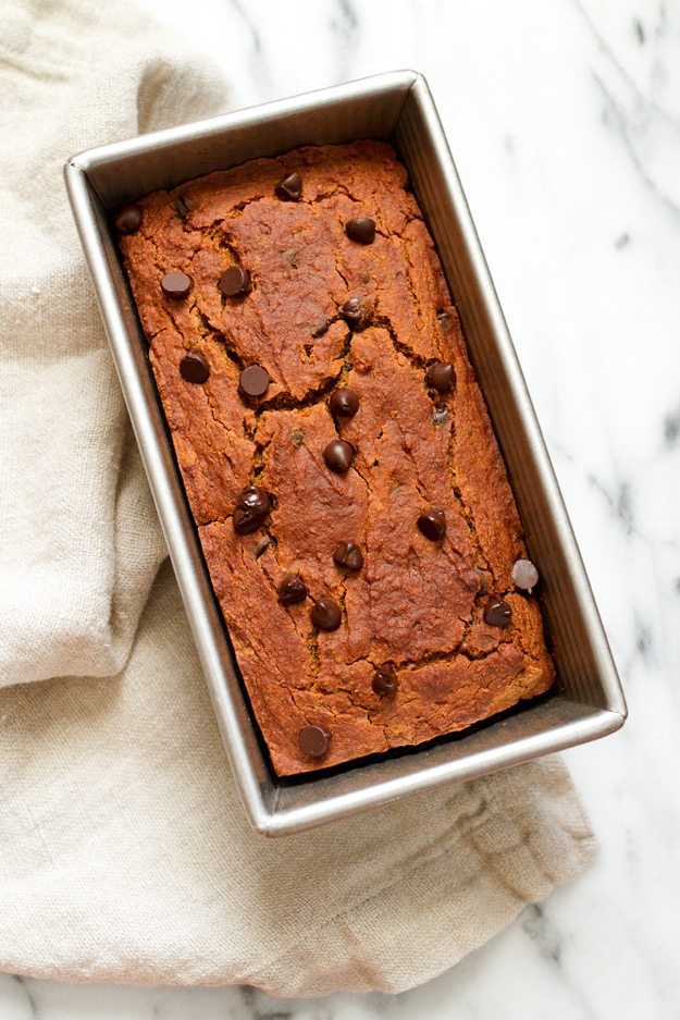 Spiced with cinnamon, nutmeg, ginger and allspice this moist and tender chocolate chip pumpkin bread is everything a pumpkin quick bread should be but a tad healthier, gluten-free and vegan. Quinoa flour pumpkin bread in a bread pan resting on a linen towel.