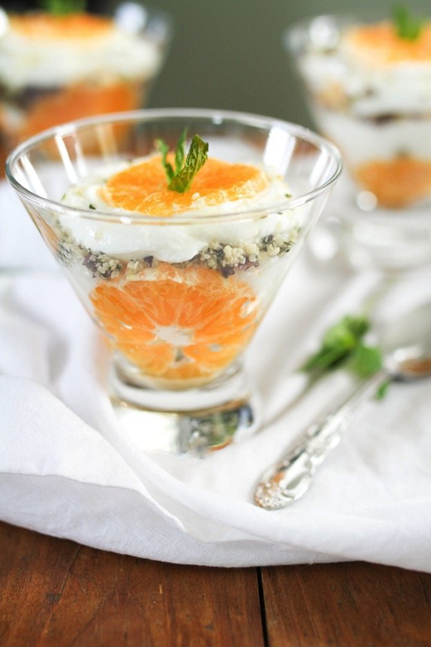 Clementine Greek Yogurt Parfaits with layers of creamy yogurt and juicy clementines along with a Hemp Heart and cacao nib crumble A side view of a glass bowl with clementine slices and greek yogurt parfait.