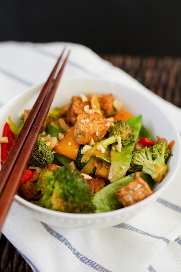 Kung Pao Tempeh Kung Pao Tempeh in a bowl with stir fried veggies and chop sticks.