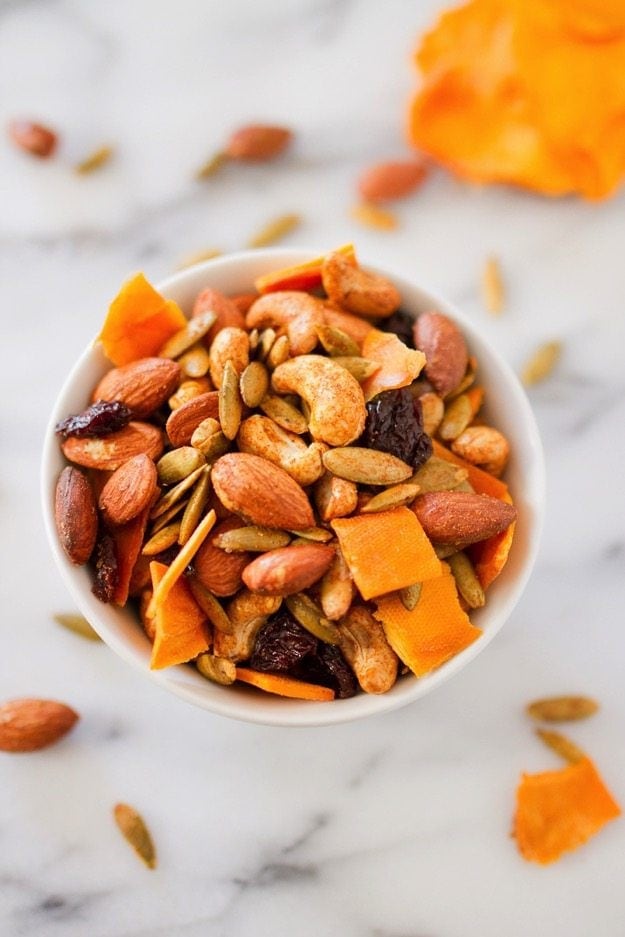 PIN THIS --> Mango Curry Trail Mix Mango curry trail mix in a white bowl on a marble counter.