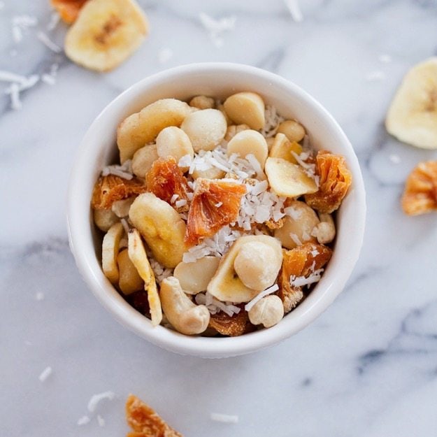 Take a trip to the tropics with this island-inspired tropical trail mix with cashews, macadamia nuts, banana chips, dried pineapple and coconut. Tropical trail mix with cashews, macadamia nuts, banana chips, dried pineapple and coconut.