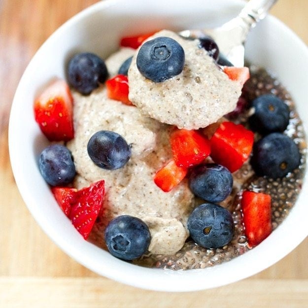 Eating Clean Creamy Breakfast Chia Pudding #dairyfree #glutenfree #vegan Cashew chia pudding served in a white bowl topped with fresh strawberries and blueberries.