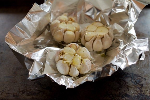 Make roasted garlic with this simple recipe! Three heads of garlic sitting on aluminum foil.