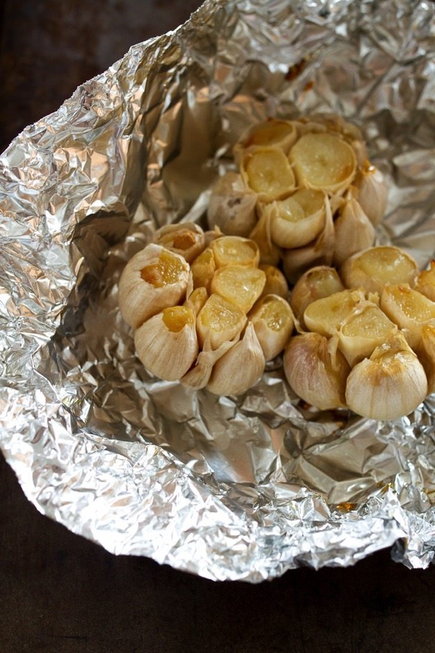 Make delicious roasted garlic! Three heads of garlic in aluminum foil after roasting.