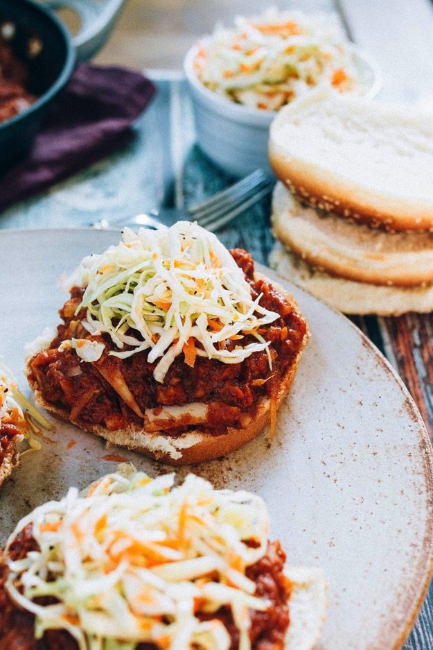 The BEST vegan BBQ sandwiches made with shredded hearts of palm, homemade BBQ sauce and a crunchy apple cider vinegar coleslaw. Hearts of palm BBQ sandwich topped with coleslaw.