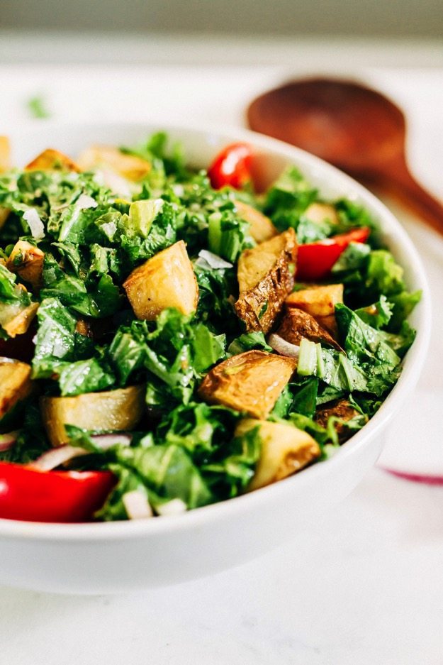 Mustard Greens Salad with Roasted Potatoes and Tomatoes Mustard Greens Salad served in a white bowl topped with Roasted Potatoes and Tomatoes