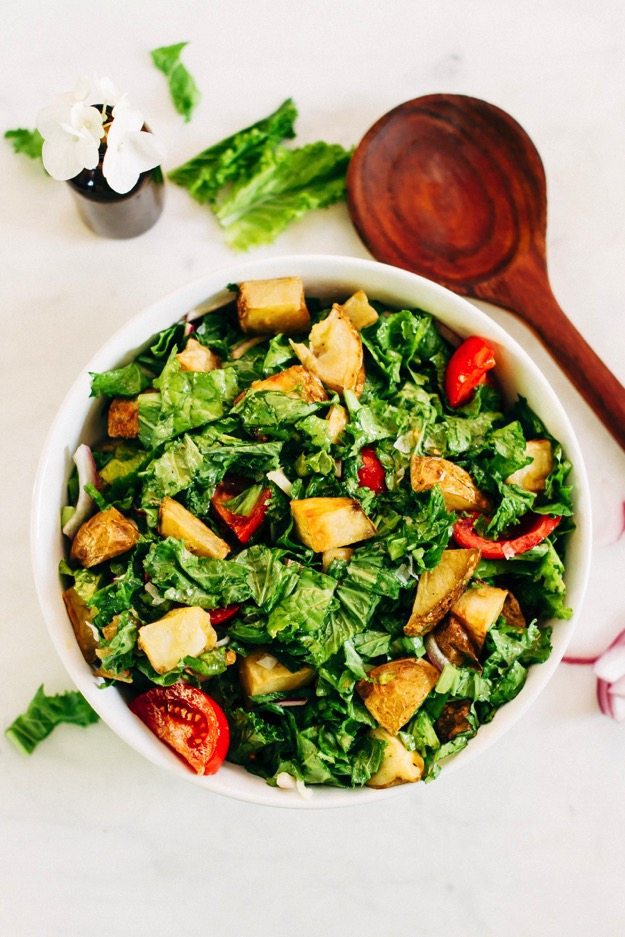 Mustard Greens Salad with Roasted Potatoes and Tomatoes Mustard Greens Salad served alongside a wooden salad spoon