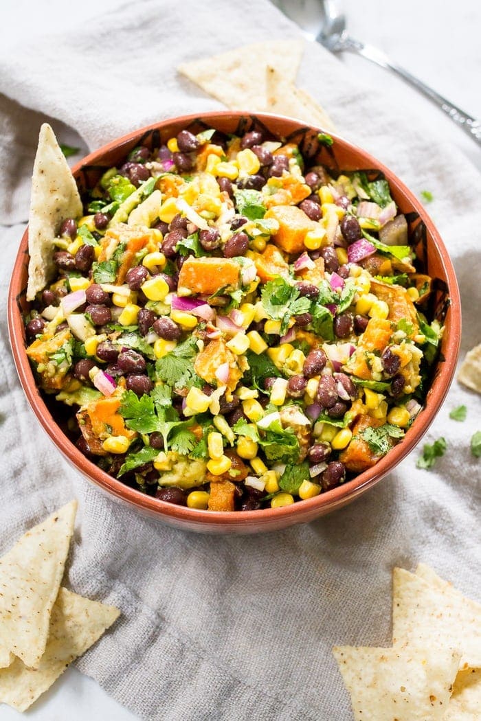 This delicious sweet potato black bean dip is loaded with flavor and perfect served with tortilla chips, as a side or as a topping for salads and tacos. #glutenfree #vegan Southwest sweet potato black bean dip served in a mixing bowl with tortilla chips.