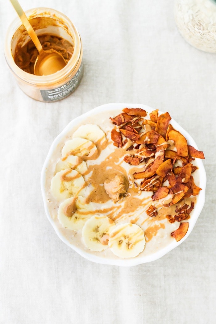 Elvis Overnight Oats with Peanut Butter, Banana and Coconut Bacon #vegan #glutenfree Peanut butter, banana and bacon overnight oats served in a white bowl drizzled with peanut butter.
