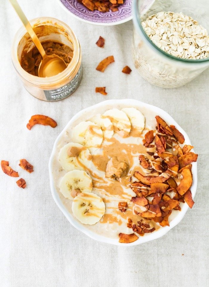 Elvis Overnight Oats with Peanut Butter, Banana and Coconut Bacon #vegan #glutenfree Peanut butter, banana and bacon overnight oats served in a white bowl with a drizzle of peanut butter.