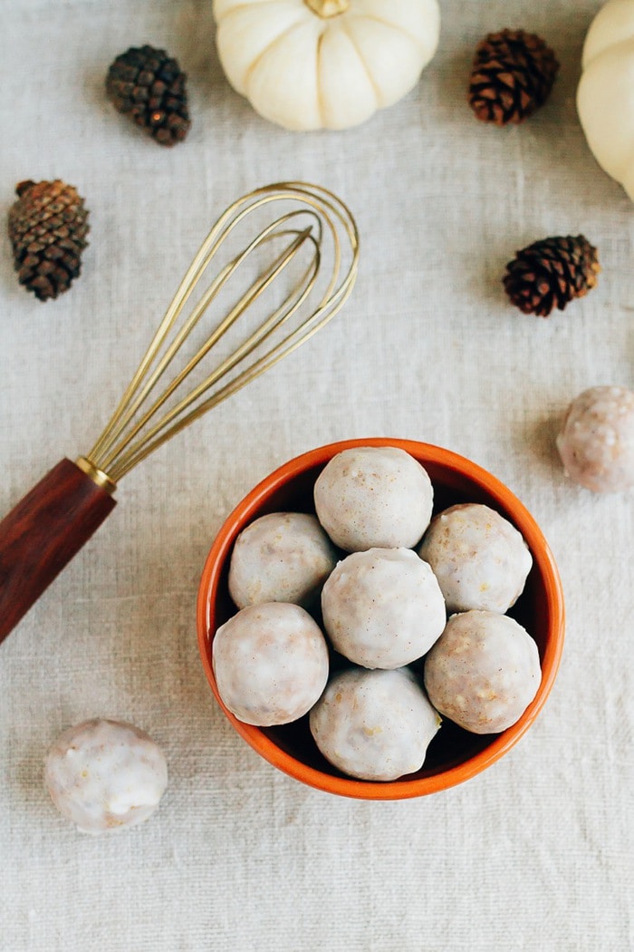 No Bake Pumpkin Spice Donut Holes // Vegan, Gluten-Free, Paleo Bowl of pumpkin spice donut holes on a table cloth with mini pumpkins, pinecones, and a whisk.