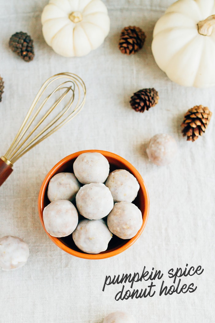 No Bake Pumpkin Spice Donut Holes // Vegan, Gluten-Free, Paleo Bowl of pumpkin spice donut holes on a table cloth with mini pumpkins, pinecones, and a whisk. Some text on the photo reads "Pumpkin Spice Donut Holes"