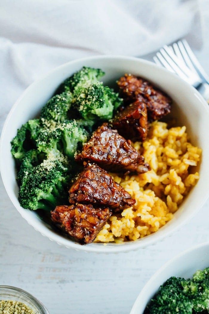 Bowl of yellow rice with tempeh and broccoli.