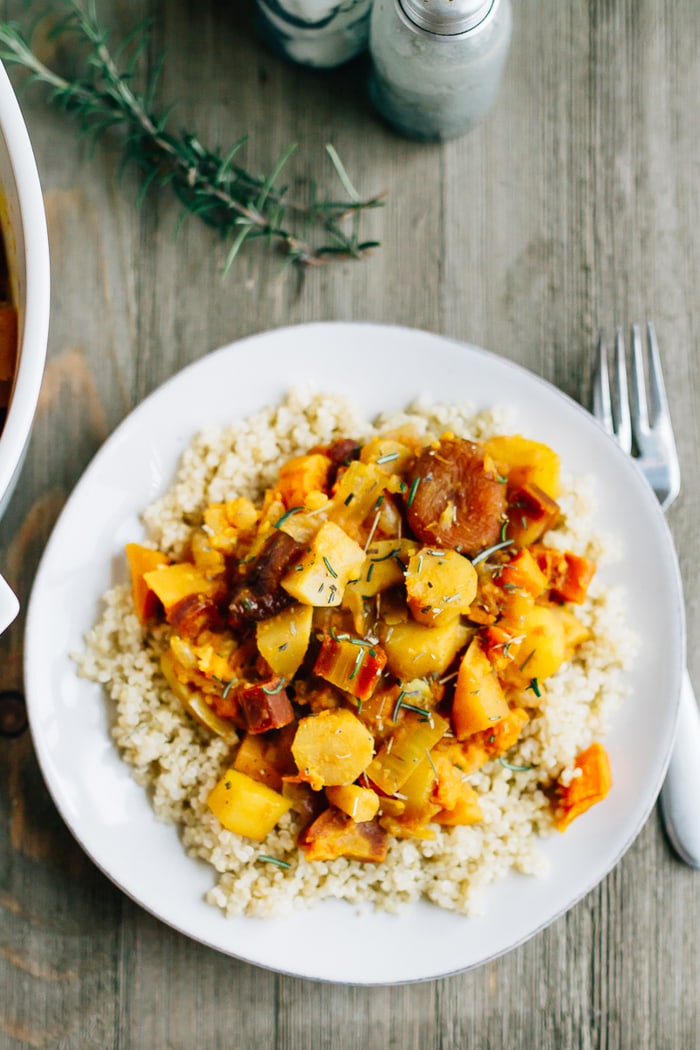 A slow simmered root vegetable tagine with apricots and rosemary! Serve this vegetarian dish as a side or over rice or quinoa for a complete meal. Root vegetable tagine with rosemary and apricots served over a plate of brown rice.