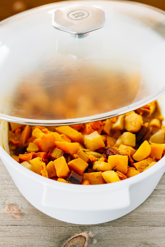A slow simmered root vegetable tagine with apricots and rosemary! Serve this vegetarian dish as a side or over rice or quinoa for a complete meal. Dutch oven with roasted root vegetables and dried apricots and rosemary.