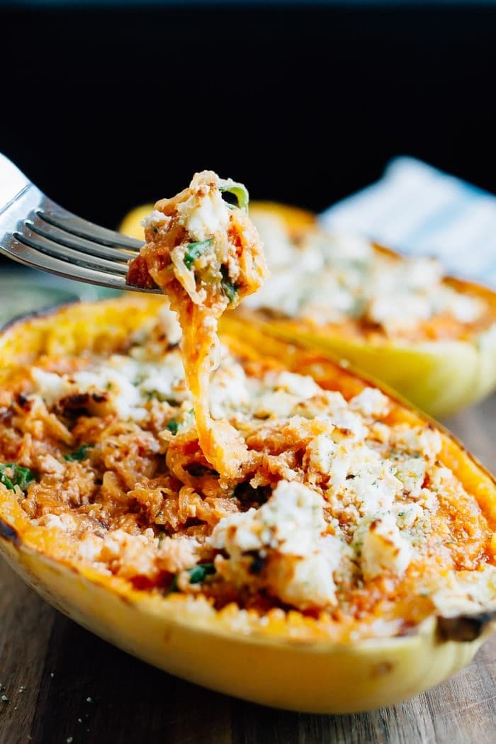 Turn spaghetti squash into a meatless meal with this recipe for stuffed SPAGHETTI SQUASH LASAGNA BOWLS. Made with vegan ricotta and hemp parmesan. Fork taking a spoonful of spaghetti squash from a lasagna spaghetti squash boat.